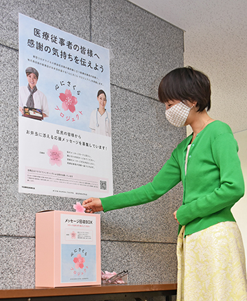 メッセージボックスにカードを投函する女性の写真