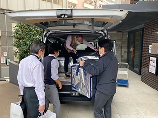 弁当を車に詰め込んでいる様子の写真