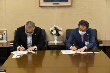 署名する青木英二目黒区長と裕幸計装株式会社代表取締役社長の太田隆三