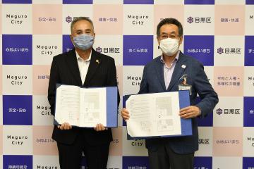 パネル前で協定書を手に持ち並ぶ青木英二目黒区長と裕幸計装株式会社 代表取締役社長 太田隆三