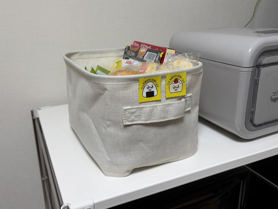 お菓子やレトルト食品など常温のもので期限が近付いたものを涙目デザインを貼り付けた箱にまとめた画像