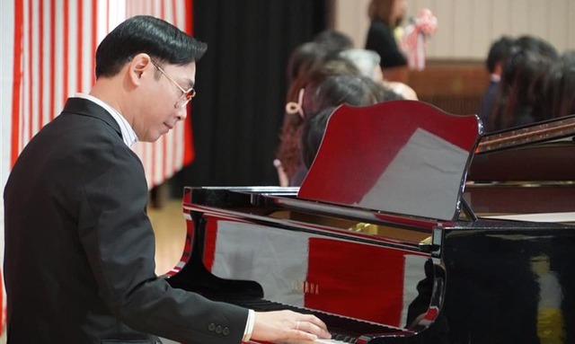 ピアノの前に座り、開校100周年記念歌「ずっとずっと 油面の空の下で」を伴奏するクラムボンのミトさん。