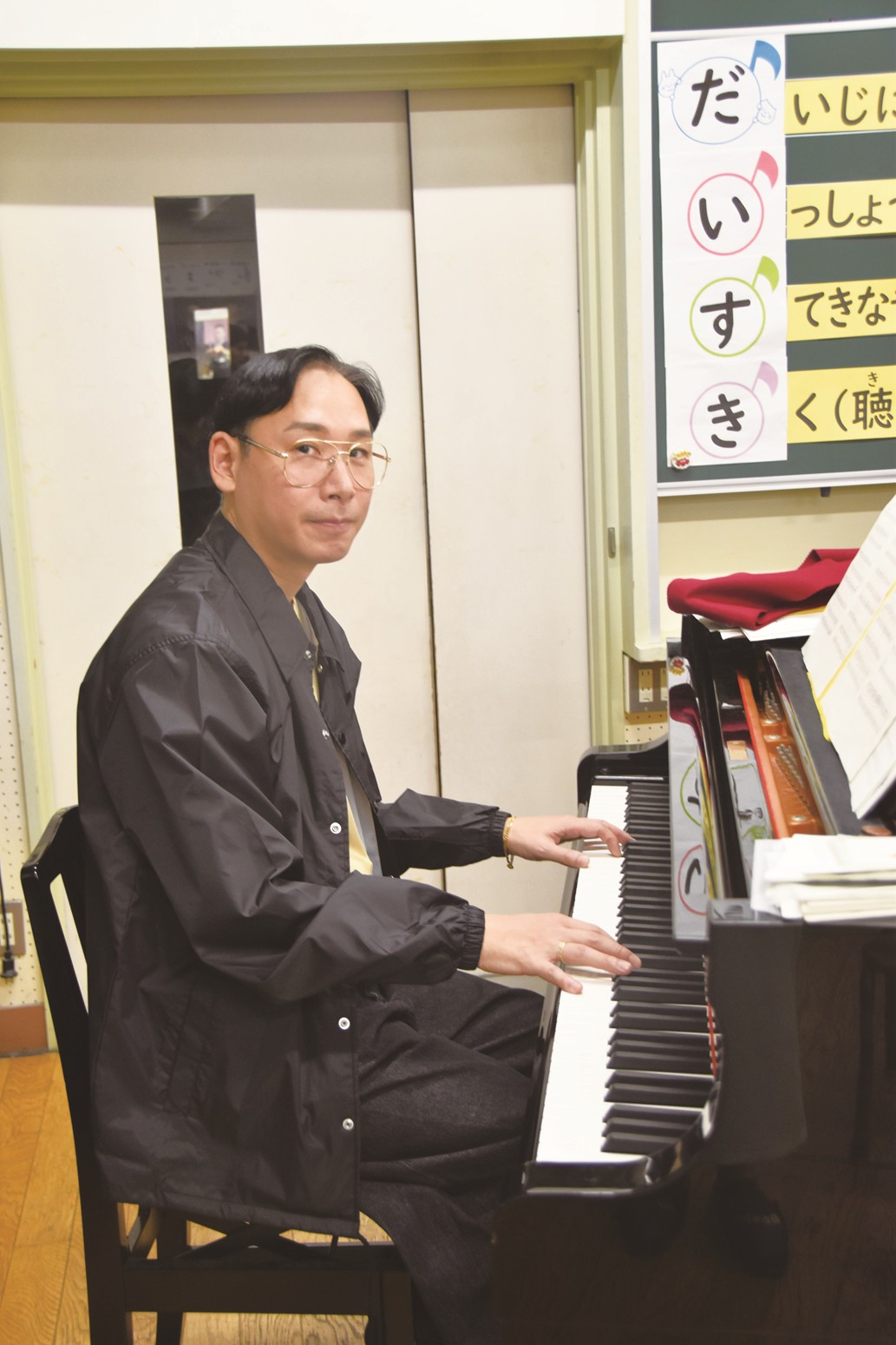 ミトさんの写真。手をピアノに添えて微笑んでいます。