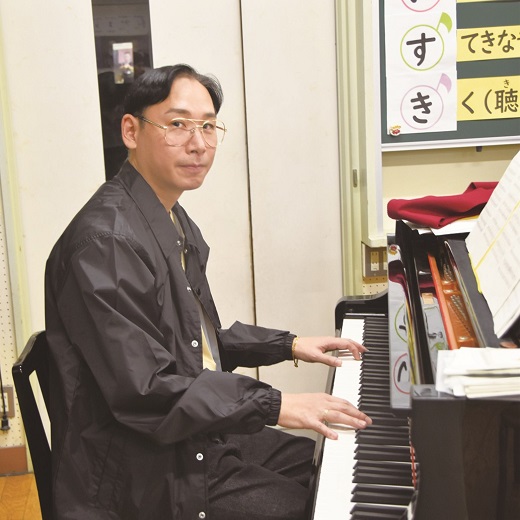 ミトさんの写真。手をピアノに添えて微笑んでいます。