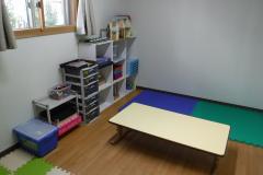 高窓の壁側には遊具が棚に収められている写真。