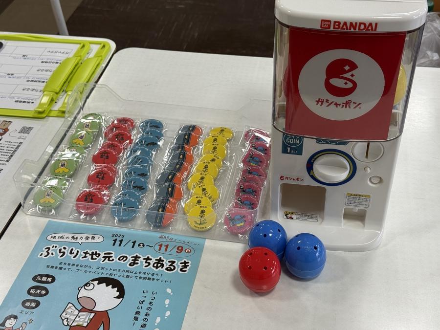 ゴールイベント会場の景品(缶バッチ)と景品を引くガシャポン