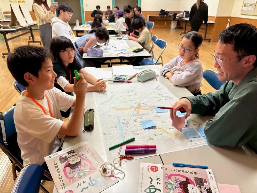 3人の子どもとプロクリエイターが楽しそうに紙面編集の会議をしている様子
